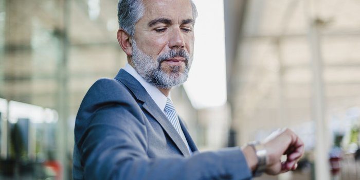 Man in a suit looking at his watch, managing his time.