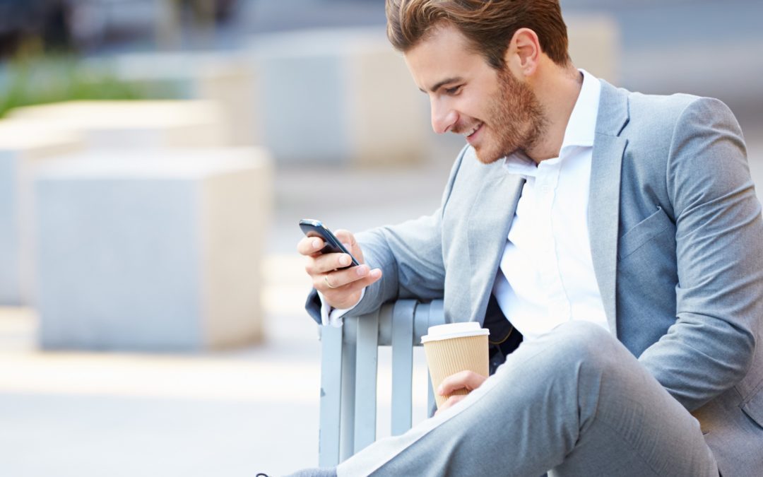 Young professional man sitting on bench looking at phone